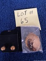 Photo showing the gold-tone fairy pendant necklace in a pouch and the pair of gold-tone clip-on earrings on a black backing card.