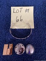 Photo of the silver bangle bracelet and two pairs of clip-on earrings with handwritten lot number 66 on note.