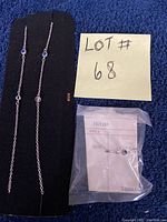 Photo showing the full length of the silver necklace with five blue sapphire-like stones and the sapphire ring in original packaging with label.