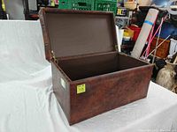 Open lid of brown rectangular storage chest showing interior storage space.