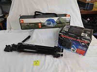 Camping set showing all three items: Ozark Trail 3-person tent in bag, Velbon Victory 450 tripod folded, and Super X 12V portable stove in box