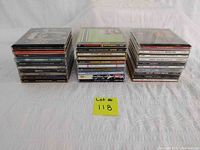 Photo of 30 stacked music CD jewel cases arranged in three stacks on a white surface.