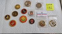 12 coins laid out on a white paper towel with various military and commemorative designs, some in wrapping