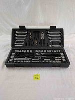 Open tool case showing two mirrored sides with assortment of combination wrenches on top, pliers in center, and socket wrenches and screwdriver bits on bottom