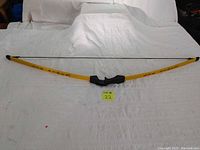 Full view of yellow Barnett Lil Sioux bow laid on white surface, showing full length and grip detail.