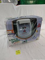 Front view of Bissell Little Green ProHeat TurboBrush cleaner in box showing product name and features on packaging.