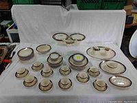 Full layout of the china set including cups, saucers, plates, bowls, and serving pieces set on white background.
