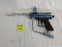 Full side view of the blue Orion VL paintball marker with silver barrel, black ergonomic grip wrapped with plastic, and connected hose.