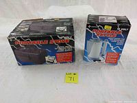 Two boxed items side by side: Superex Portable Stove and Portable Kettle, both 12 Volt, designed for camping use.