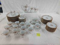 Full set of china pieces including plates, cups, saucers, and serving pieces arranged on table.