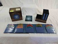 Complete set of DVDs spread out showing colorful discs in blue sleeves, outer decorative box and bonus discs.