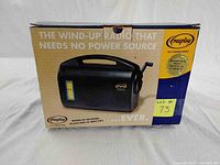 Photo showing front and one side of the original box featuring black Freeplay wind-up radio image, emphasizing no power needed and energy wind-up mechanism.