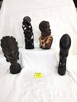 Front view of four hand carved wooden African bust sculptures arranged on white cloth