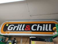 Front view of the sign showing 'Grill & Chill' text with orange border and black background, showing size and structure.