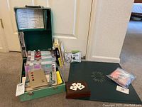 Full view of green case open showing aluminum card holders, bridge books, magnetic board, playing cards and accessories on carpeted floor.