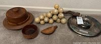Photo showing all items: lidded carved wood dish with plates underneath, small carved wood bowl, small scoop, decorative stone grapes, and metal lazy Susan tray.