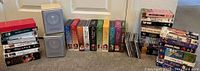 Wide shot showing complete Little House on the Prairie DVD series and stacks of VHS movies and DVDs arranged on carpet against a white door.