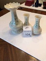 Three Belleek Shamrock porcelain vases of varying heights displayed together on table.