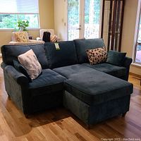 Front view of blue velvet sectional sofa with chaise and pillows