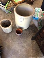 Overview photo showing large and smaller stoneware pots on concrete floor with adjacent bag of play sand and two small pots