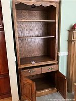 Front view of the wooden display cabinet showing two open shelves, two drawers, and double-door lower storage.