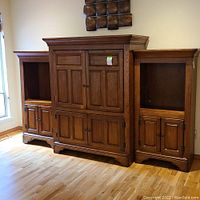 Full view of the three-piece wooden entertainment center with wall art above