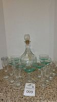 Full lot image showing Jack Daniel's branded glass decanter, margarita glasses, champagne glasses with lids, and shot glasses arranged on a granite surface.
