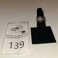 Stacked Silpada sterling silver rings displayed on black ring holder with auction lot card visible.