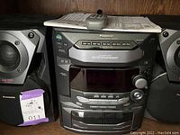 Front view of Panasonic stereo system showing 5-disc CD changer, tape player, control buttons, and display.