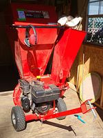 Front/right three-quarter view of red Troy-Bilt chipper shredder showing engine, wheels, hopper
