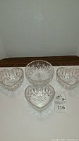 One Waterford Crystal round bowl surrounded by three heart-shaped serving bowls arranged on white surface with lot tag