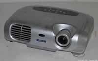 Side front angle view of silver Epson projector showing lens, ventilation, and control buttons on top