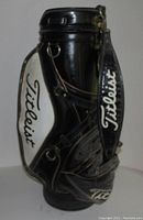 Side view of a black and white Titleist golf bag showing the brand name on multiple locations and the overall good condition.