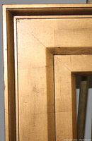 Close-up of the corner showing the gold finish and layered stepped design with visible surface textures and minor marks.