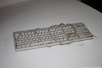Full view of the white wired desktop keyboard, showing wear and dirt