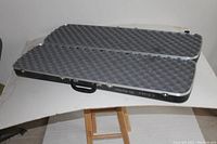 Open black hard traveling case with metal trim and foam padding inside to protect firearm.