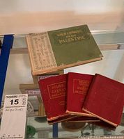 Photo showing Wild Flowers from Palestine book and three red cloth-bound Miniature Library books stacked together.
