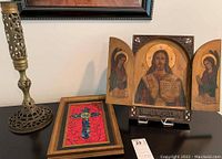 All three items arranged on tabletop: brass pillar, framed mosaic cross, wood triptych