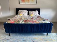 Front view of navy blue velvet upholstered bed frame with floral bedding