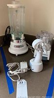 Black & Decker electric can opener base, Cuisinart Mini-Prep food processor, Waring Kitchen Classics blender with glass pitcher, all on counter with cords.