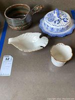 Photo showing ceramic cheese plate with cover by Henriot Quimper, white and blue decorative cover, hand-thrown pottery pot, Lenox bird dish, small white ceramic dish with gold trim