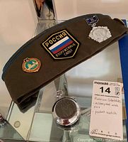 Overall view of Russian military side cap with pins and pocket watch on display.