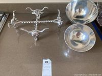 Two polished Nambe metal serving bowls and a casserole carrier with steer heads