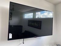 Front view of LG 60-inch television mounted on wall, showing black screen and frame.