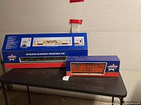 Two boxed G scale model train cars: USA Trains Extruded Aluminum Passenger Car and Santa Fe boxcar.