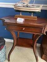 Full view of the wood accent table with a drawer and the decorative boat base lamp placed on top.