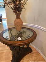 Full view of round hall table showing mahogany frame, glass top and giraffe sculpture base with floral arrangement on top