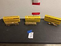 Three unpainted brass car shells and chassis in front of three yellow E. Suydam & Co boxes