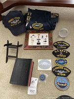 Overview of lot showing cap, patches, framed pins, book, folded clothes and loose patches.