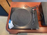Top view of the Mitsubishi automatic return turntable showing the rubber platter mat, tonearm, and connected wires.